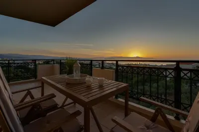 a table and chairs on a balcony with a sunset at Aelia Sea View in Chania Town