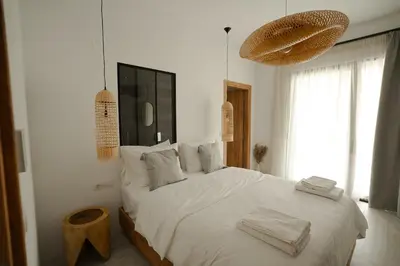 a bedroom with a large bed with white sheets and pillows at Athos Guesthouse in Stalos