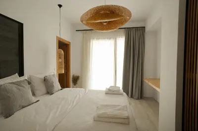 a bedroom with a large white bed with a large window at Athos Guesthouse in Stalos