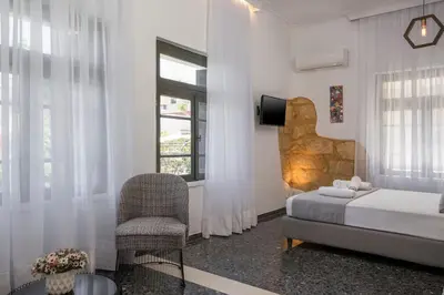 a bedroom with a bed and a chair and a window at Casa Αrezio in Chania Town