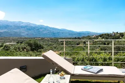 a balcony with a chair and a table and mountains at Upper View Villa, with private pool in Chania Town