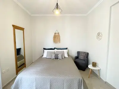 a bedroom with a large bed and a chair at Thali central apartment with parking in Chania Town