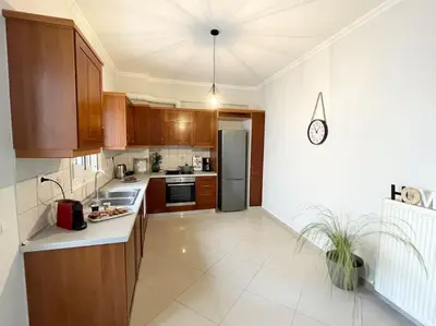 a kitchen with wooden cabinets and a stainless steel refrigerator at Thali central apartment with parking in Chania Town