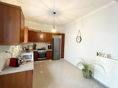 a kitchen with wooden cabinets and a stainless steel refrigerator at Thali central apartment with parking in Chania Town