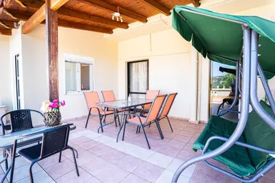 a patio with tables and chairs and a green umbrella at Villa Marianna Lygides in Ayiá