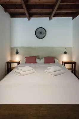 a bedroom with a large white bed with a clock on the wall at Μilia Mountain retreat in Vlátos