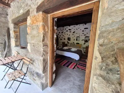 a bedroom with a bed and a stone wall at Μilia Mountain retreat in Vlátos