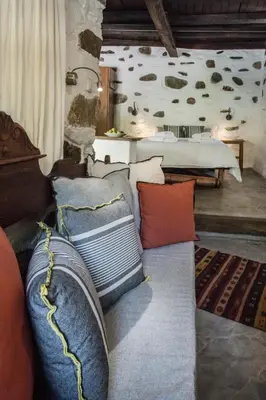 a living room with a couch with pillows and a bed at Μilia Mountain retreat in Vlátos