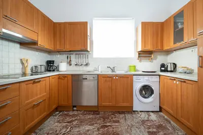 a kitchen with wooden cabinets and a washer and dryer at Clio Townhouse in Chania Town