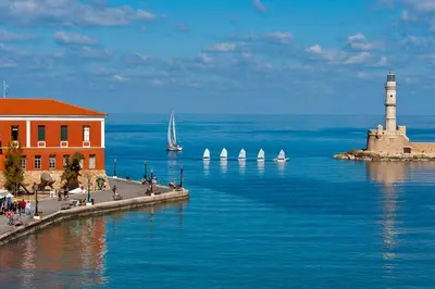 a lighthouse on the water with sailboats in the ocean at Clio Townhouse in Chania Town