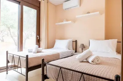 two beds in a room with a window at Terra Blue Suites - Dimitra in Kalyves