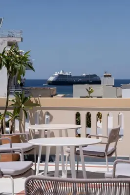 a group of tables and chairs on a balcony with a cruise ship at Bouquet Luxury Rooms in Chania Town