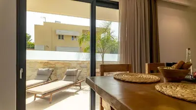a living room with a table and chairs and a balcony at D PALM Premium Living - Kalathas, Chania in Chania Town