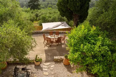 a patio with a table and chairs and trees at liofito village house in Pemónia