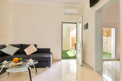 a living room with a black couch and a glass table at Cretan Fun in Stalos