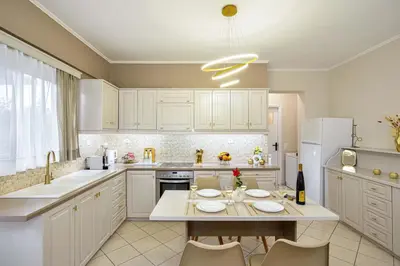 a kitchen with white cabinets and a table with chairs at La Fleur in Chania Town