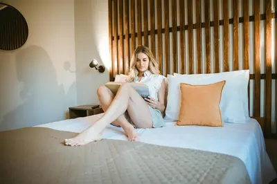 a woman sitting on a bed reading a book at Chania Dream House in Chania Town