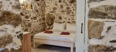 a bedroom with a bed and a stone wall at Mesavlia Traditional Stone House in Mesávlia