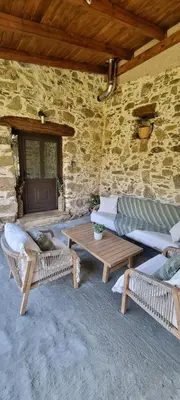 a patio with couches and tables in a stone wall at Mesavlia Traditional Stone House in Mesávlia