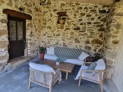 a patio with a couch and chairs and a stone wall at Mesavlia Traditional Stone House in Mesávlia