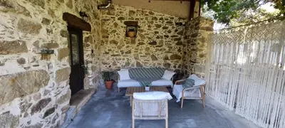 a patio with a table and chairs in a stone wall at Mesavlia Traditional Stone House in Mesávlia