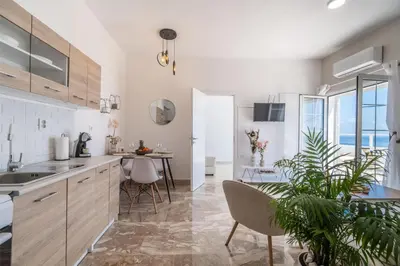 a kitchen with white cabinets and a table with a plant at Avra Sfakia Apartments in Khóra Sfakíon