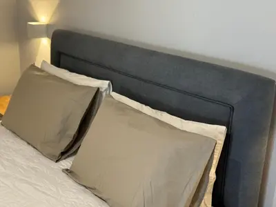 a bed with a gray headboard with two pillows at Sofia Rooms in Palaiochóra