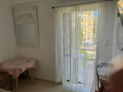 a room with a window with a curtain and a table at Sofia Rooms in Palaiochóra
