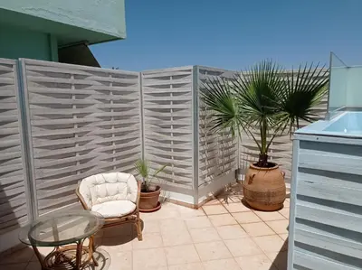 a patio with a chair and a glass table at City Apartment with heated rooftop Pool in Chania Town