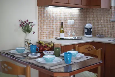 a kitchen with a table with plates and a bottle of wine at City Apartment with heated rooftop Pool in Chania Town