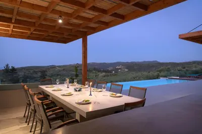 a dining table and chairs on a patio with a view at Blue Zone Villa, a SeaView Sanctuary with Pool, By ThinkVilla in Chania Town
