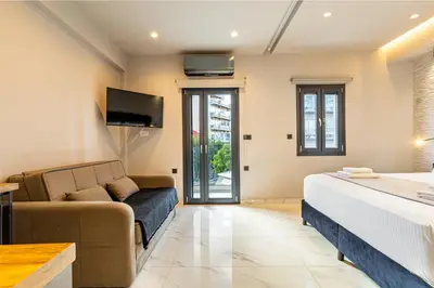 a bedroom with a bed and a couch and a tv at Melina's - Urban Luxury 2-Bath Apt with 2 Balconies - Heart of Chania in Chania Town