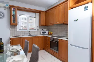 a kitchen with wooden cabinets and a white refrigerator at Niman Beachside Apartments in Chania Town