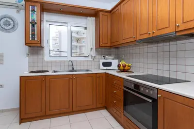 a kitchen with wooden cabinets and a sink and a microwave at Niman Beachside Apartments in Chania Town