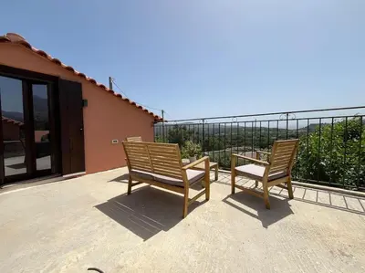 two wooden chairs and a table on a balcony at Vrysses Lodge Michael Stelianos in Vryses