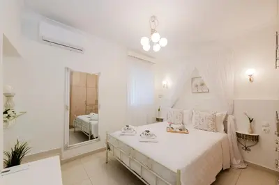 a white bedroom with a large bed and a mirror at Villa Noelia in Rogdhiá
