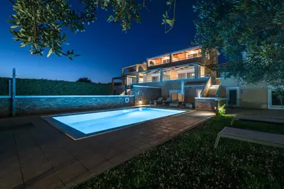 a house with a swimming pool at night at Koralia's Villas in Chorafakia