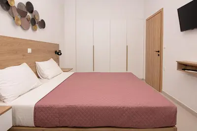 a bedroom with a large bed with a pink blanket at Rikanthos Stone Sea View Apartment ΙΙ in Kissamos