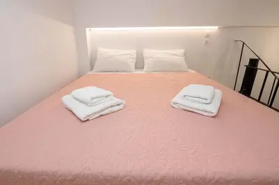a pink bed with two towels on top of it at Rikanthos Stone Sea View Apartment ΙΙ in Kissamos