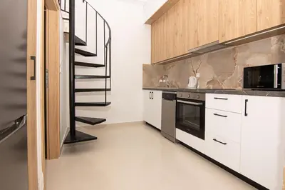 a kitchen with white cabinets and a spiral staircase at Rikanthos Stone Sea View Apartment ΙΙ in Kissamos