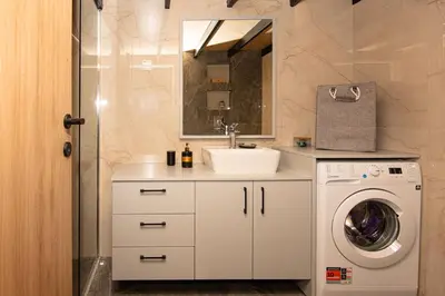 a bathroom with a sink and a washing machine at Rikanthos Stone Sea View Apartment ΙΙ in Kissamos