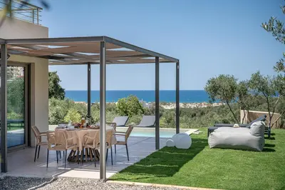 a patio with a table and chairs and a view of the ocean at Seaview villa with pool in nature next to Platanias in Plataniás