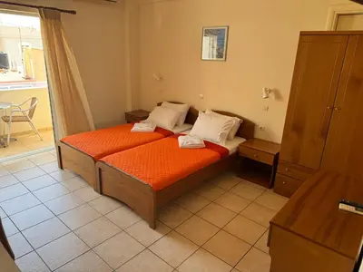 a bedroom with a bed with orange sheets and white pillows at Michalis Studios & Aparntments in Palaiochóra