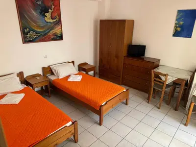 a room with two beds and a table and a tv at Michalis Studios & Aparntments in Palaiochóra