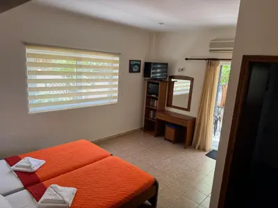a bedroom with an orange bed and a window at Michalis Studios & Aparntments in Palaiochóra