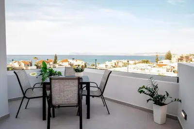 a balcony with a table and chairs and a view of the ocean at Villa Icons in Agia Marina Nea Kydonias