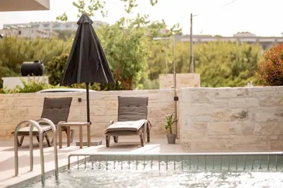 a patio with two chairs and an umbrella next to a pool at Villa Icons in Agia Marina Nea Kydonias