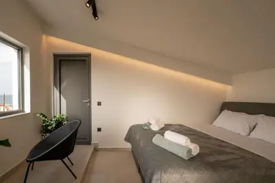 a bedroom with a bed and a chair and a window at Villa Icons in Agia Marina Nea Kydonias