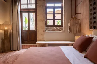 a bedroom with a bed and a window and a bench at Qualia Slowlife Suites in Chania Town