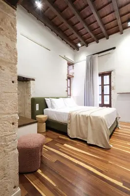 a bedroom with a large bed and a chair at Qualia Slowlife Suites in Chania Town